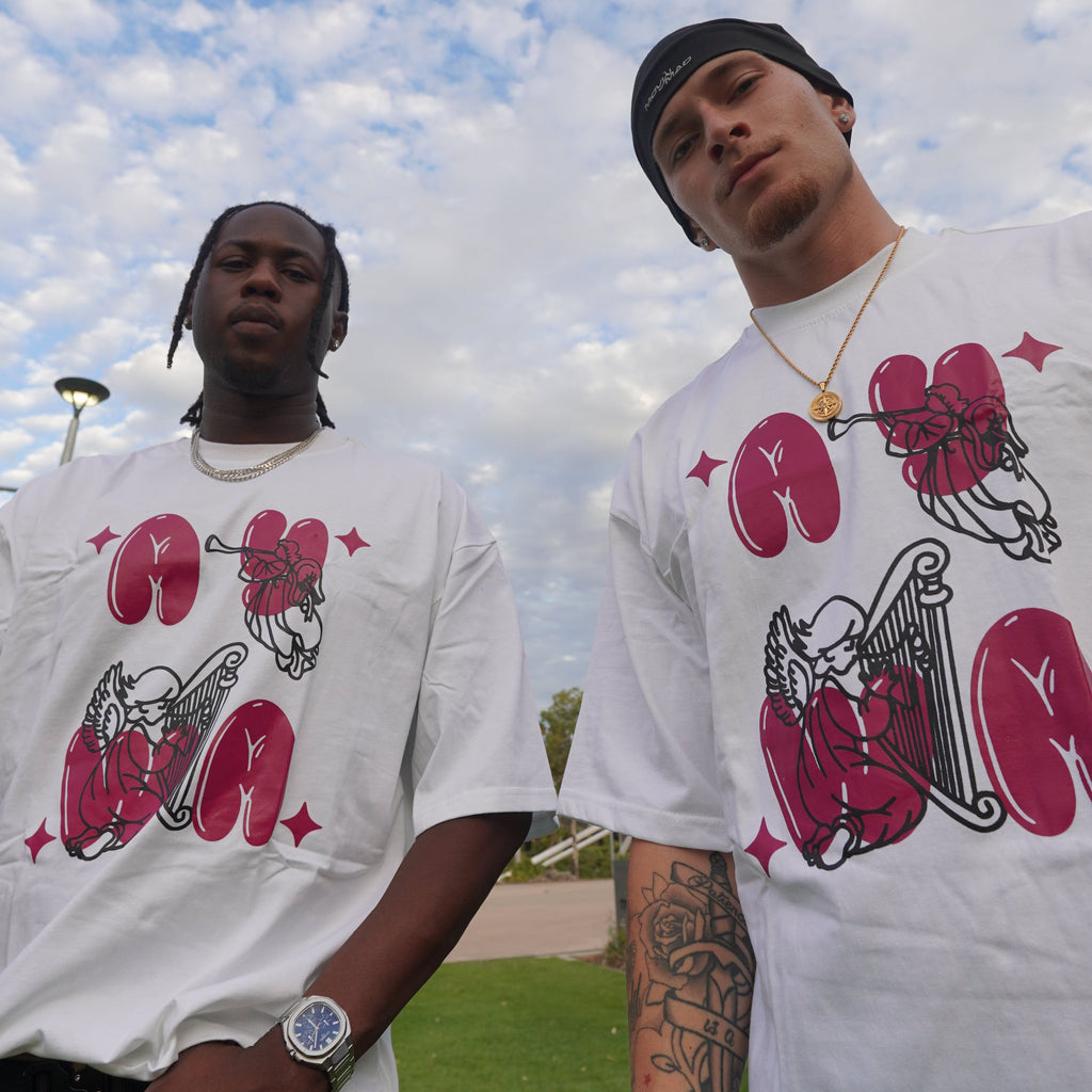 Two people wearing matching t-shirts with a graphic design against a blue sky with clouds.